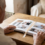 Abuelo de espaldas con las manos sobre un álbum de fotos de lino natural abierto en la mesa del salón